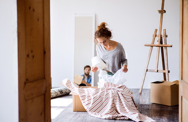 Young couple moving in new house, unpacking boxes.