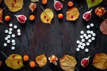 Obraz na płótnie Canvas Concept of cold autumn - pills, leaves on dark wood