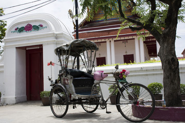 Fototapeta na wymiar Vintage retro tricycle bike or rickshaw of thai style at front of gate of Wat Songtham Worawihan