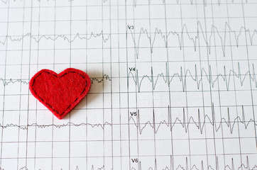 Electrocardiogram on paper.  Red heart made of fabric