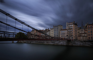 Fototapeta na wymiar Old footbridge (Passerelle) over the Saone river in Lyon, France, during stormy weather.