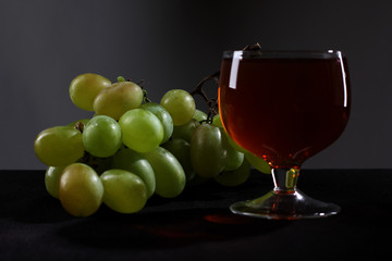 Bottle glass of wine and grapes on black background