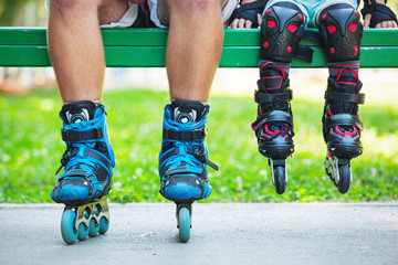 Close up photo of legs in inline skates sitting on bench. Learning skating concept image.