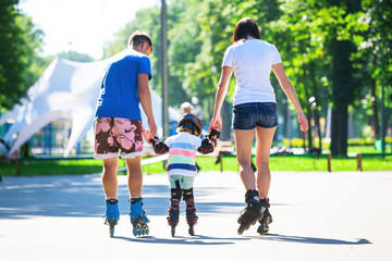 Cute baby boy and his mom learning inline skating with skating instructor.