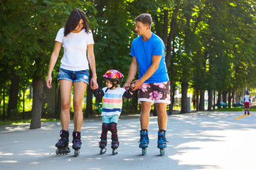 Cute baby boy and his mom learning inline skating with skating instructor.