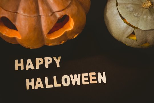 Happy Halloween text by jack o lanterns over black background