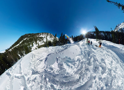 Snowboarder freerider jumping from snow ramp. Wide-angle aerial panorama