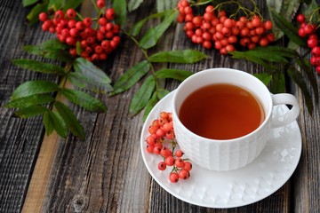 Obraz na płótnie Canvas Delicious cup of tea and Rowan berries on a wooden table