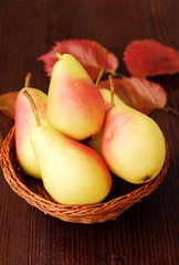 Juicy ripe yellow pears and autumn leaves in a wooden table  