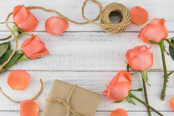 Brown gift boxes and rope with orange roses on white wood background with copy space
