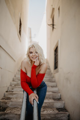 Beauty tanned and stylish young woman standing on steps in sunny bright summer day. Travel and vacation concept.