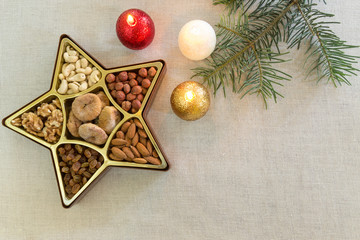 Star shaped box with Christmas decoration, different kinds of nuts, candles and a gift, selective focus