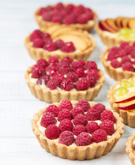 Tart with custard and berries, raspberry, light blue background, vertical, selective focus
