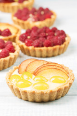 Tart with custard and berries, raspberry, light blue background, vertical, selective focus