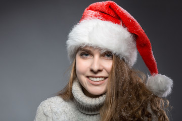 hübsches Mädchen lächelt im Pulli mit Weihnachtsmütze