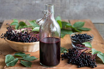 A bottle of homemade elderberry syrup on a wooden table - obrazy, fototapety, plakaty
