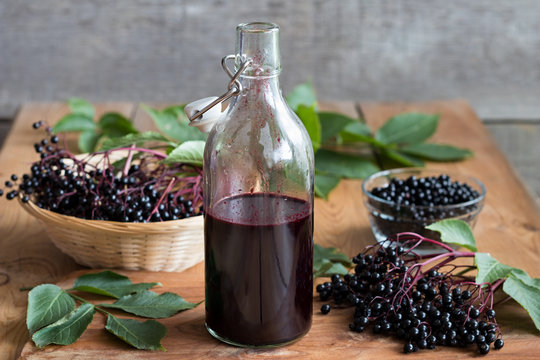A bottle of homemade elderberry syrup on a wooden table