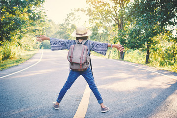 Happy Asian girl backpack in the road and forest background, Relax time on holiday concept travel ,color of vintage tone and soft focus