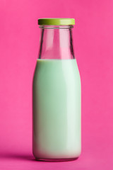 Green milk bottle on pink background.
