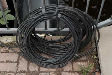 Black industrial rubber cable bundle outdoors next to a fence