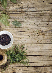 Tomillo, hojas de laurel y bol con bayas de pimienta negra sobre fondo de madera envejecida
