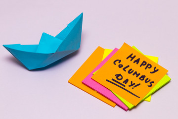 Happy Columbus Day note with an orange and a paper boat