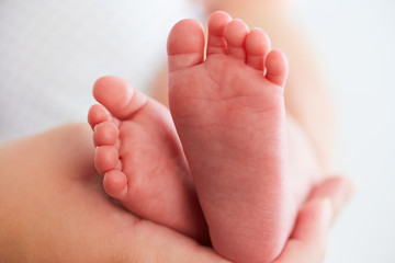 Baby feet in mother's hands. The concept of motherhood