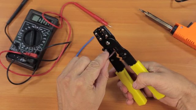 Master electrician removes insulation from copper wires with a special tool.