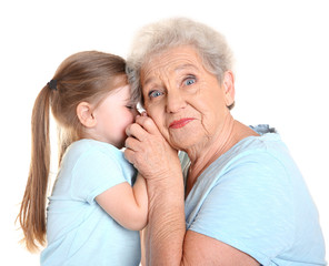 Cute little girl with her grandmother on white background