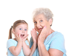Cute little girl with her grandmother on white background