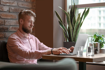 Young blogger with laptop working in cafe