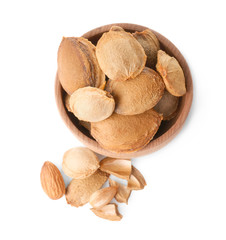 Bowl with apricot kernels on white background