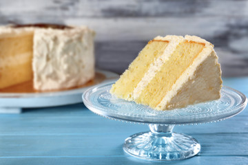 Slice of delicious vanilla cake on blue wooden table