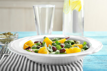Superfood salad with yellow tomato, beans and zucchini on wooden table