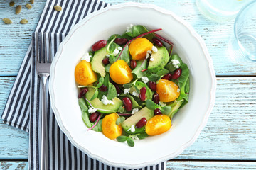 Superfood salad with yellow tomato, beans and zucchini on wooden background