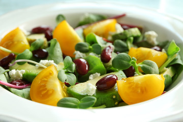 Superfood salad with yellow tomato, beans and zucchini in white ceramic plate, closeup