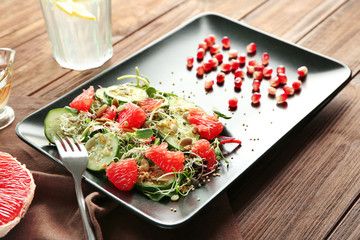 Superfood salad with cucumber, pomegranate seeds and grapefruit on wooden background