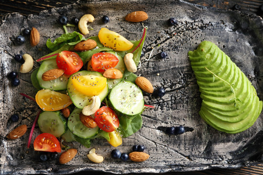 Superfood salad with tomato, cucumber and zucchini on handmade plate, top view