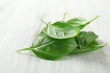 Pile of green fresh organic basil leaves on wooden background