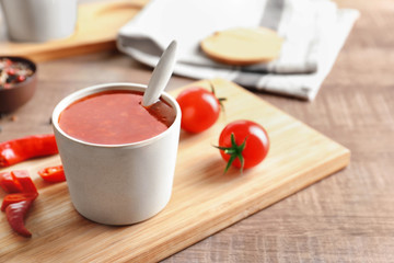 Composition with chili sauce in cup on table