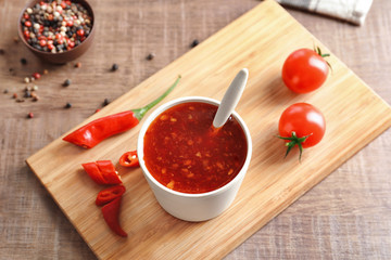 Composition with chili sauce in cup on table