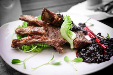 Delicious ribs served with sauce on plate, closeup