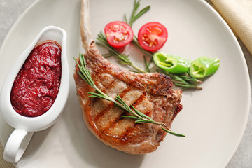 Delicious rib served with sauce and vegetables on plate