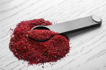 Maqui berry powder and measuring spoon on wooden background