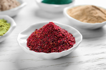 Maqui berry powder in white ceramic bowl on wooden background