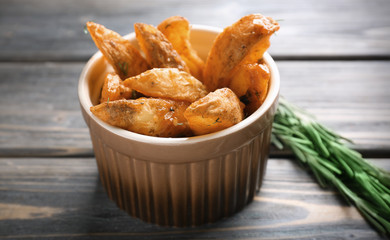 Bowl with delicious baked potato wedges on table