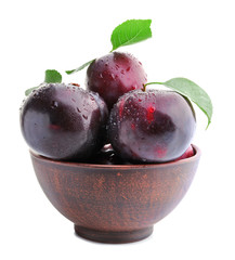 Bowl with fresh ripe plums on white background