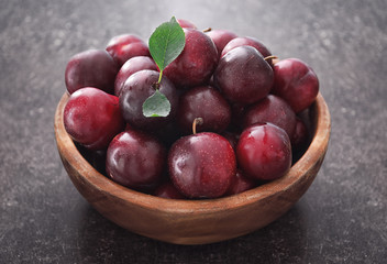 Fototapeta na wymiar Bowl with fresh ripe plums on table