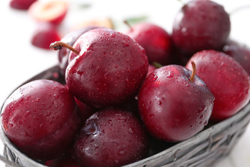Basket with fresh ripe plums, closeup