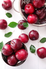 Composition with fresh ripe plums on white background